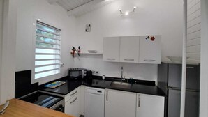 Une cuisine de taille réduite avec des meubles blancs, un plan de travail noir, un four à micro-ondes, un évier et un lave-vaisselle.