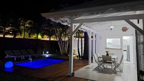 Un espace extérieur abrité comprenant une piscine, des chaises longues et une table à manger.