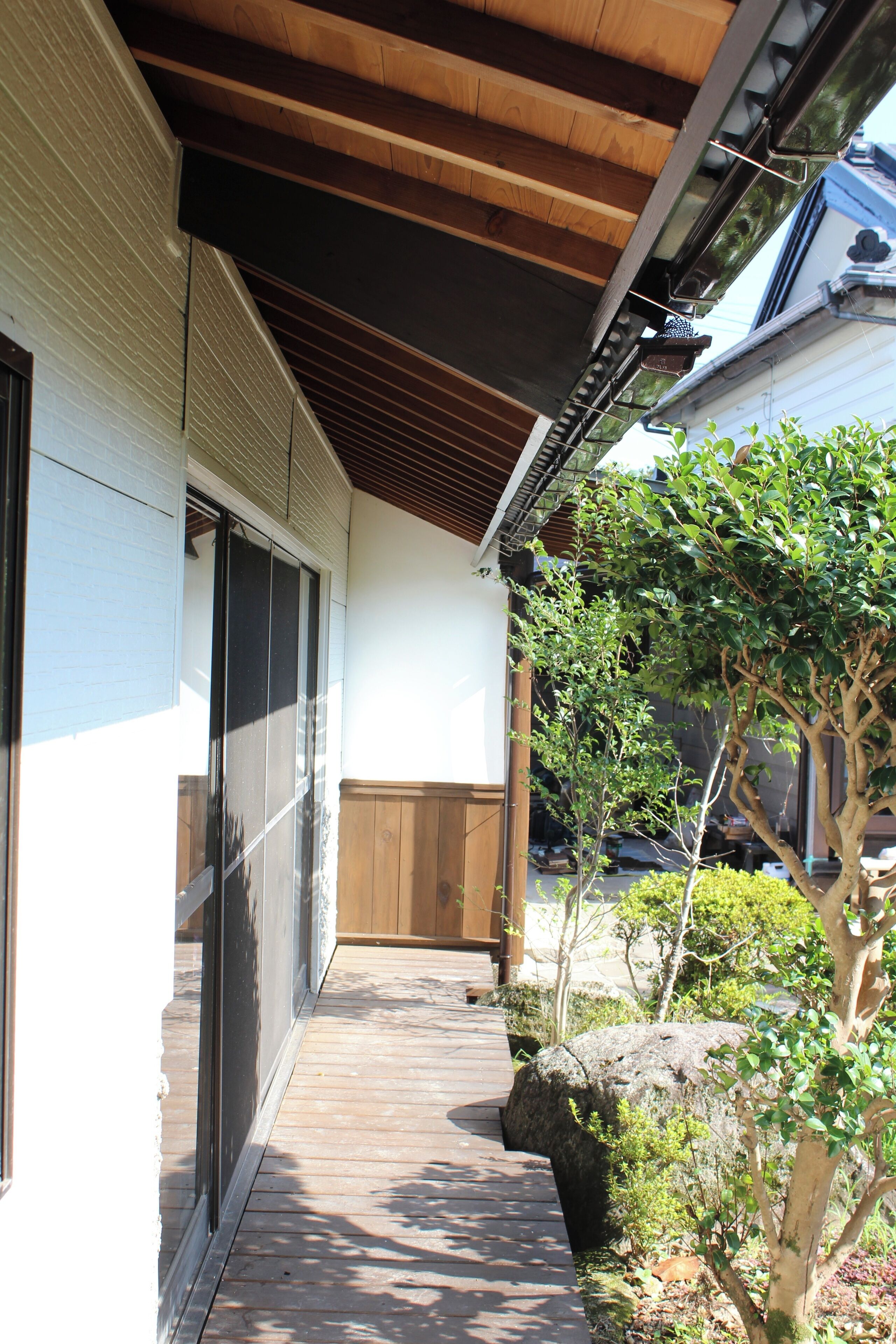 A wooden deck leading to a building with sliding glass doors and a covered porch.
