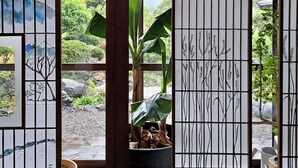 Une pièce de style japonais traditionnel, avec un sol recouvert de tatamis, des paravents en papier de riz (shoji) et une vue sur un jardin.