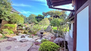Un jardin japonais traditionnel, agrémenté d’une structure en bois, de chemins de gravier, de rochers et de verdure.