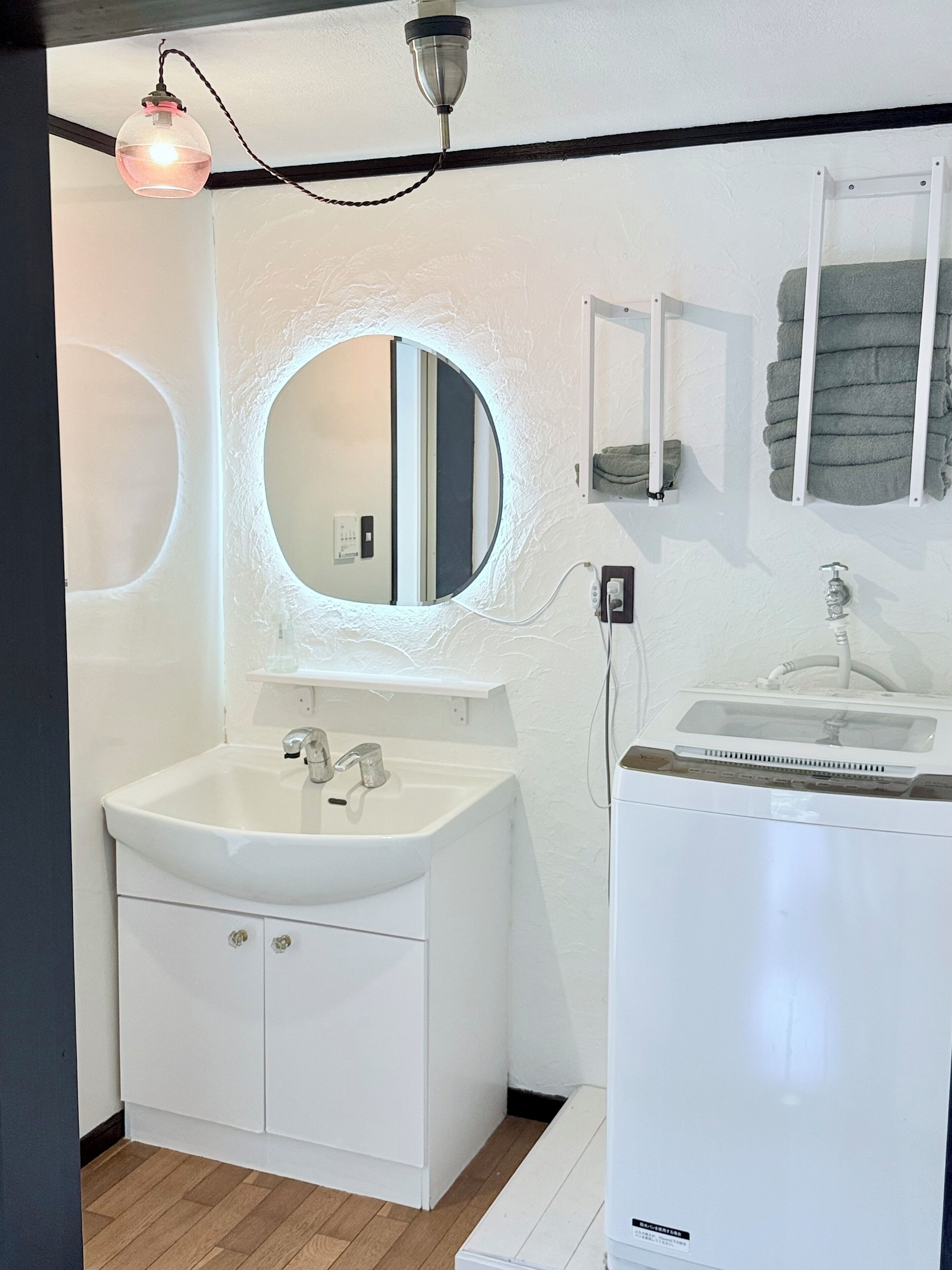 A modern bathroom with a white sink, a mirror, a towel rack, and a ceiling light fixture.