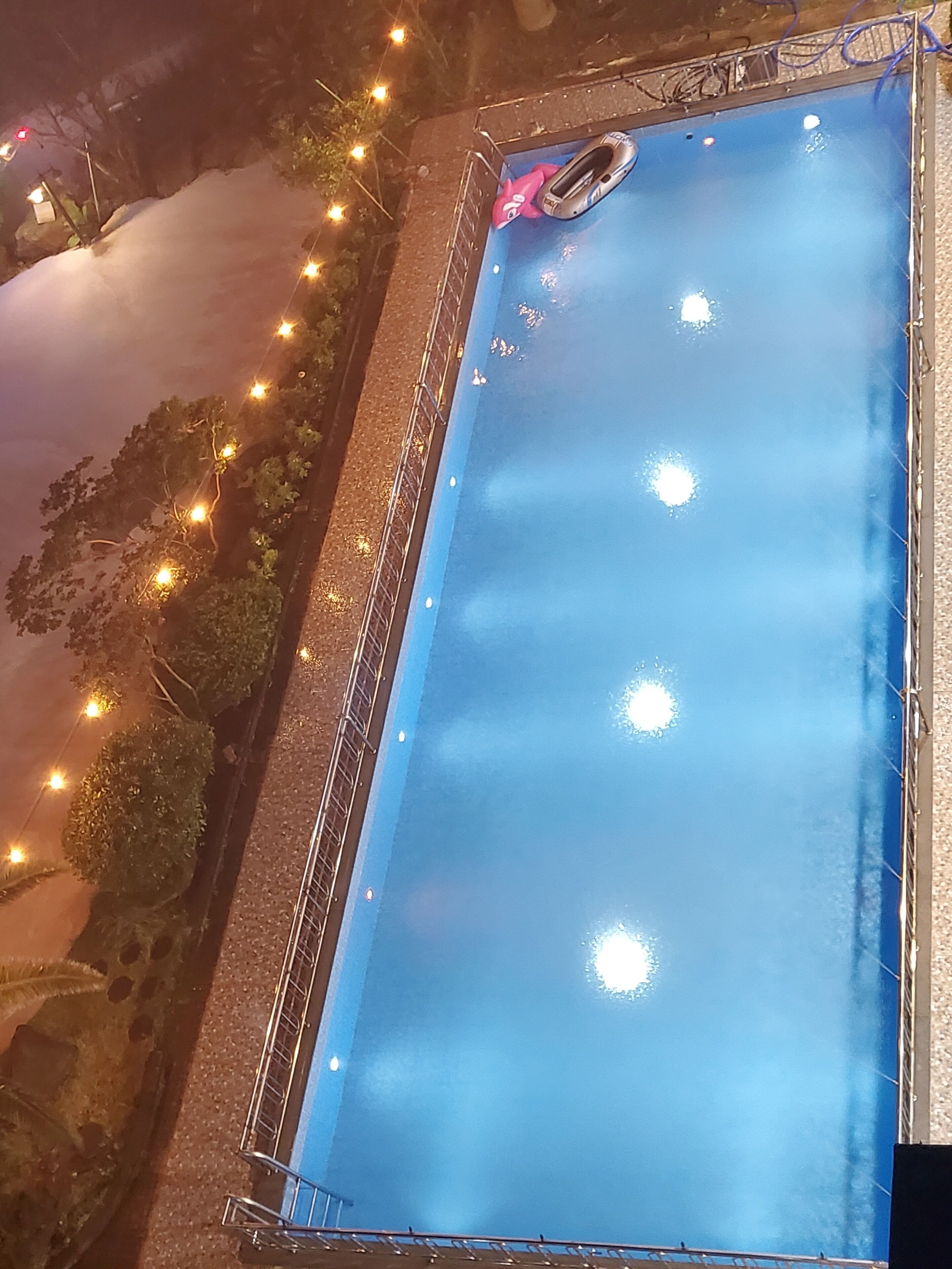 Piscina rectangular con interior azul, rodeada por una barandilla de metal.