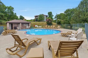 A swimming pool with lounge chairs and a small building, surrounded by trees and a hill in the background. - Golf Course View from Screened Porch, Near Silver Dollar City with Free Tickets, Gated Resort (Reeds Spring)