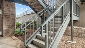 Un escalier en béton avec des rampes métalliques menant à l’entrée d’un immeuble.