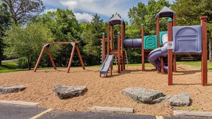 Une aire de jeux avec des balançoires, un toboggan et des structures d’escalade.