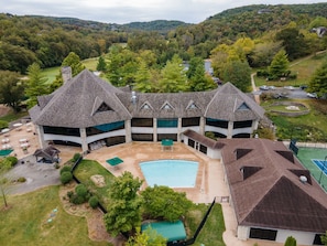A large, multi-story building with a central courtyard, a swimming pool, and a tennis court. - Golf Course View from Screened Porch, Near Silver Dollar City with Free Tickets, Gated Resort (Reeds Spring)