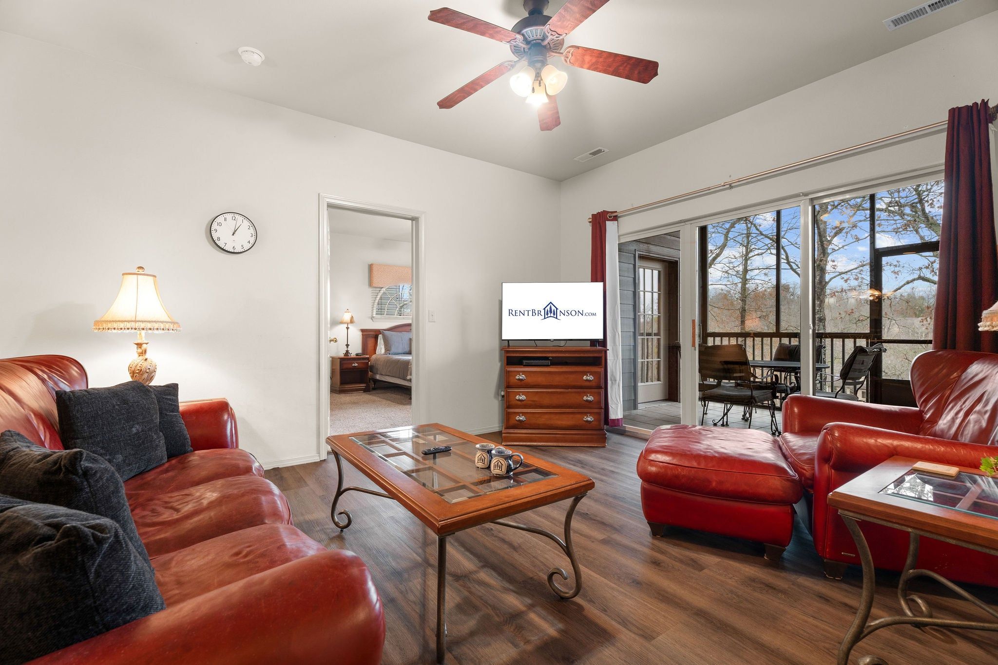 A living room with a television, leather sofas, a coffee table, and a dining area with a view.
