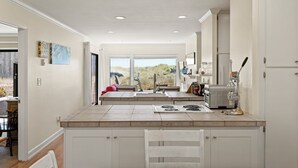 Een moderne keuken met witte kasten, een centraal eiland en uitzicht op de omgeving.