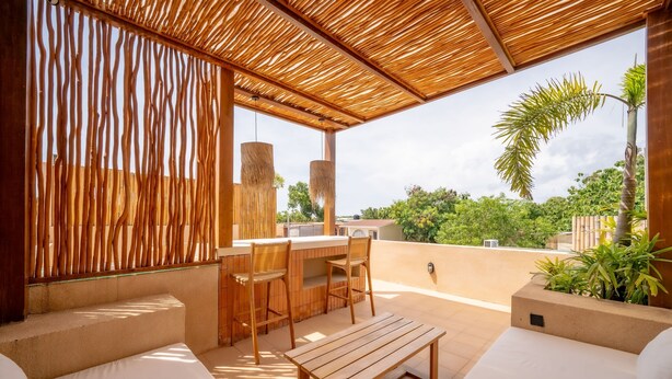 A rooftop terrace with a wooden pergola, a dining area with chairs and a table, and a view of greenery. - Villa Tierra 1 Uluwatu (Uluwatu)