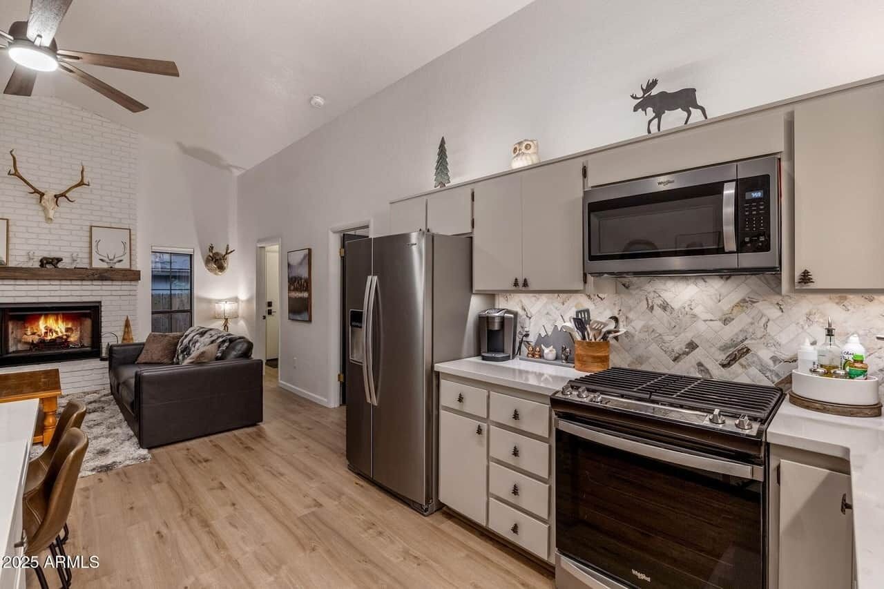 A modern kitchen with a fireplace, stainless steel appliances, and a dining area with a leather couch.