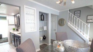 Una sala de estar moderna con una mesa de centro de vidrio, un cuenco decorativo y una escalera con barandilla blanca.