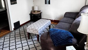Un salon équipé d’un téléviseur à écran plat, d’un canapé, d’un tapis à motifs et d’une table basse.