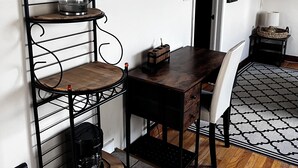 Une cuisine compacte avec une table en bois, une chaise, une machine à café et un porte-ustensiles suspendu.