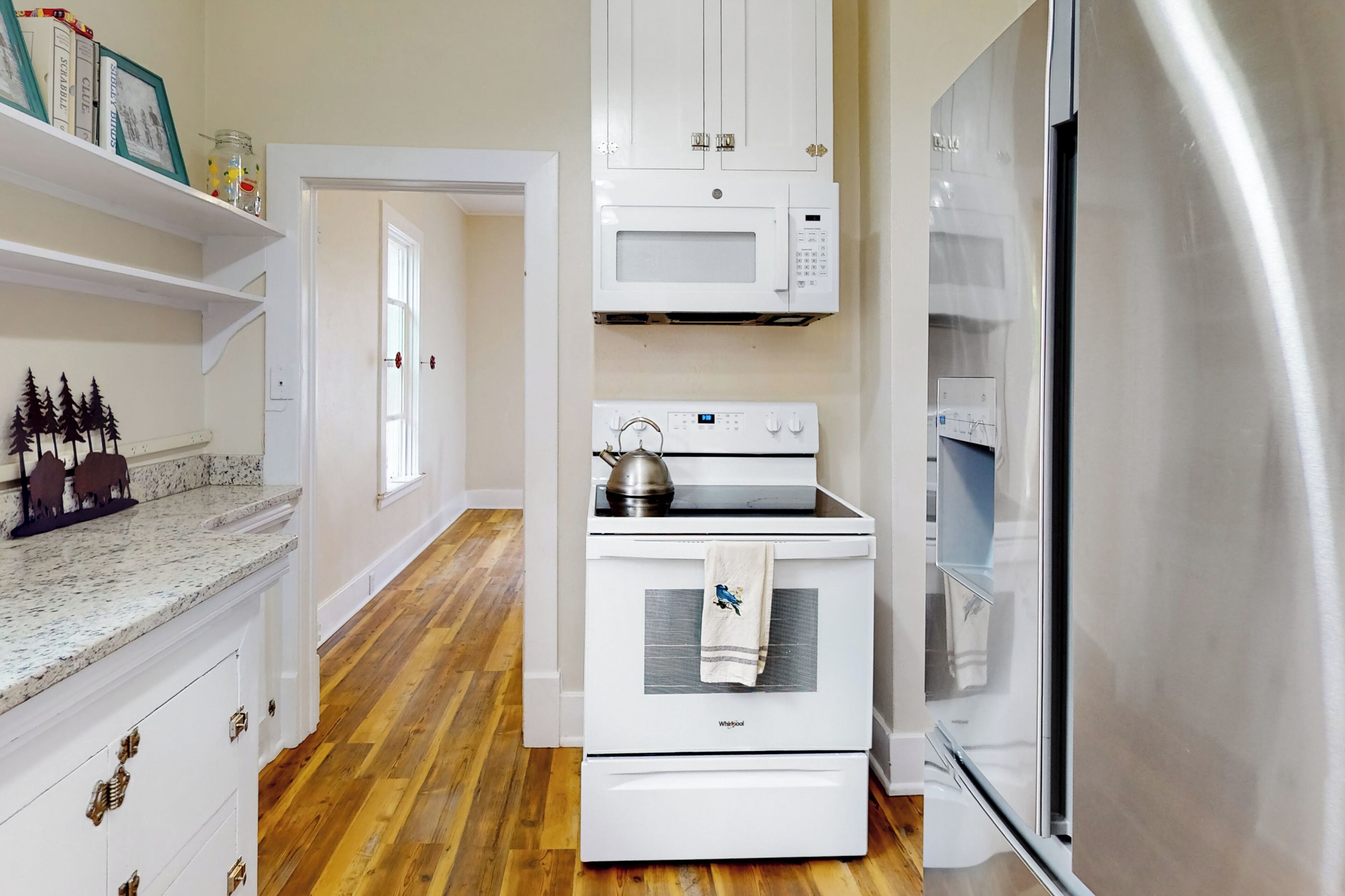 A kitchen with white cabinets, a microwave, a stove, and a stainless steel refrigerator.