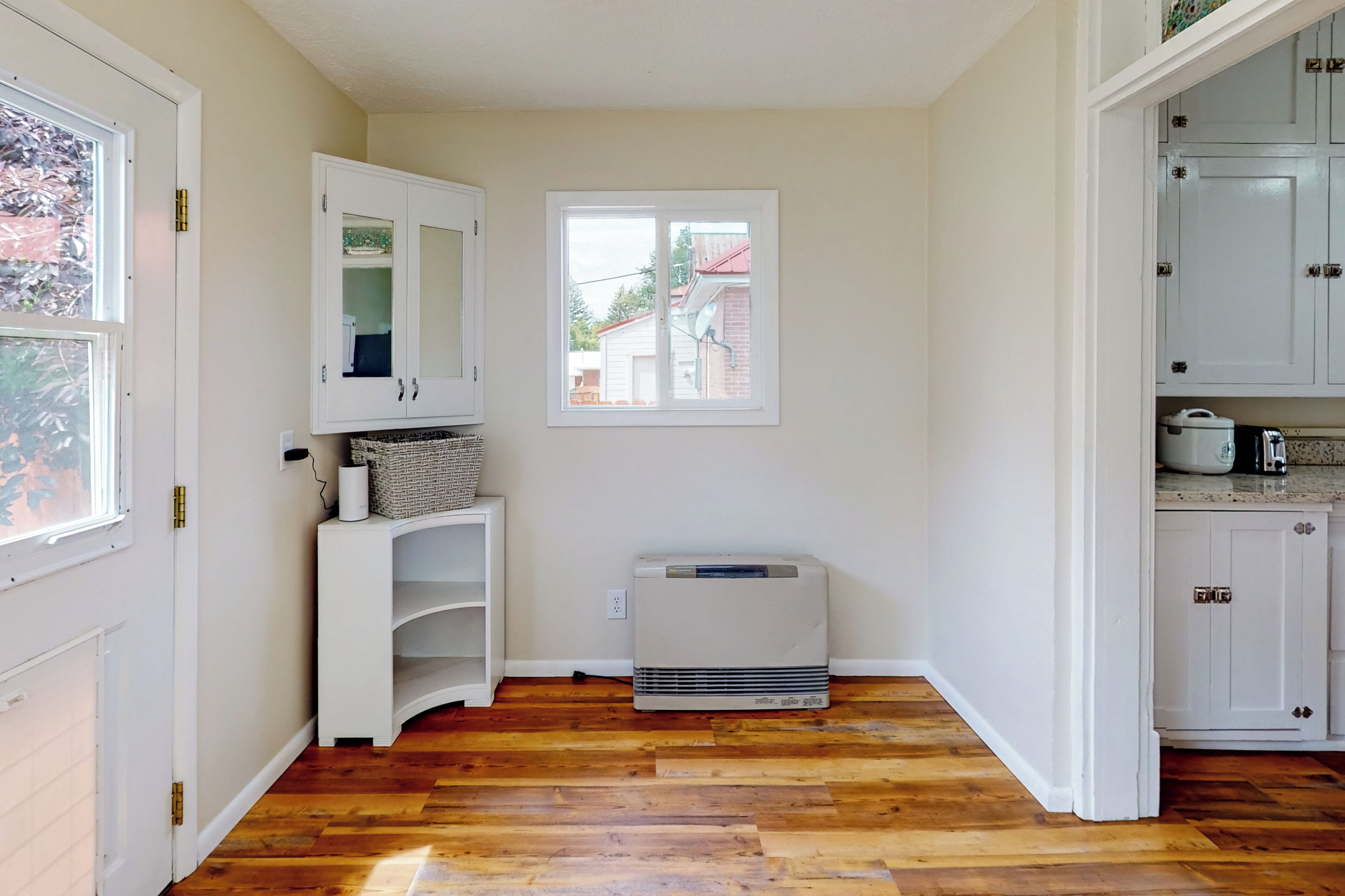 A compact kitchen with white cabinets, a window, and a built-in air conditioner.