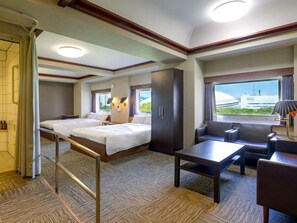 A hotel room with two beds, a sofa, a table, and a view of a building. - Koraku Garden Hotel (Tokyo)