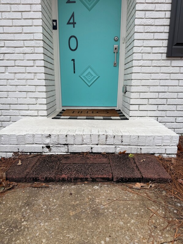 A turquoise door with the number 401, a white brick wall, and a small step leading to the door. - The Dale Cottage. 9mi to UAB & Birmingham, firepit. Pets stay free. (Fultondale)