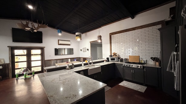 Una cocina moderna con una isla grande, armarios de madera oscura y un salpicadero de ladrillo blanco.