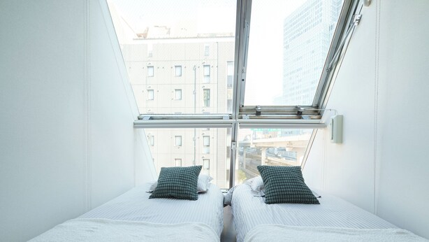 A room with two beds, a window, and a view of buildings. - 6 min to Roppongi St! Spacious 5BR apt, 12 beds,140㎡,sleeps up to 12 guests. (Roppongi, Minato)