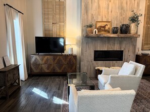 Un salon avec un téléviseur, un canapé et une cheminée.