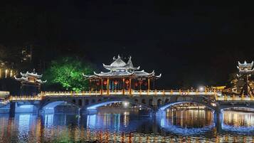 Un pabellón chino tradicional con techo de tejas, rodeado de agua e iluminado por luces.