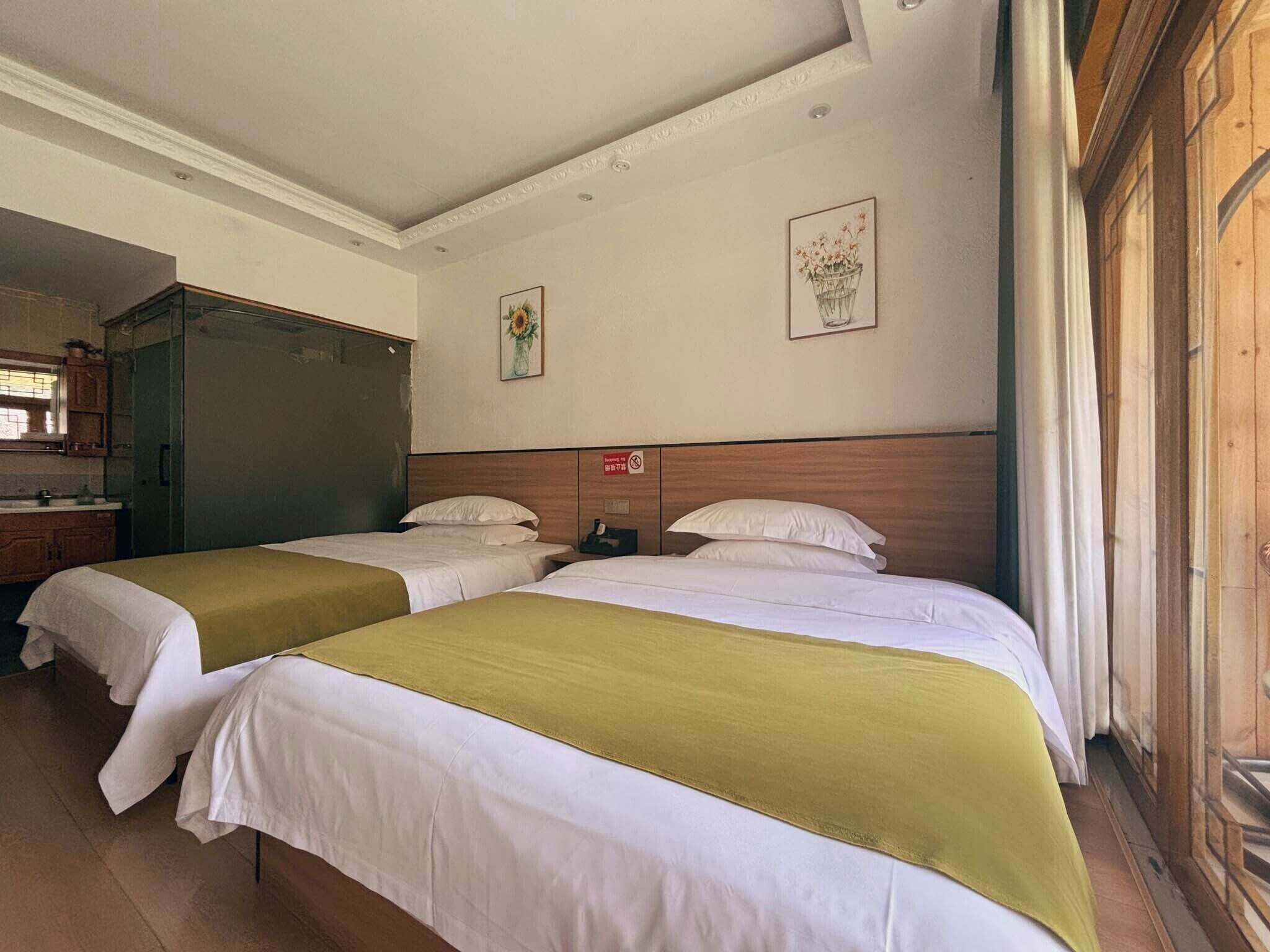 A hotel room with two beds, a wooden headboard, a small table, and a mirror.