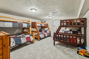 A bunk bed room with a wooden bunk bed and a lower bunk with a quilted bedspread.