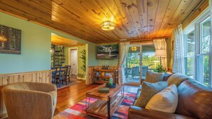 A cozy living room with a wooden ceiling, a sofa, a coffee table, and a view of the outdoors. - Summer Sale/Hot Tub/Fire Pit/Playset/Arcade/Pet Friendly/4 mins to US33 (Rockbridge)