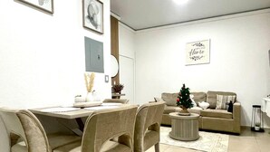 Een moderne woonkamer met een eethoek, een bank en een kleine kerstboom.