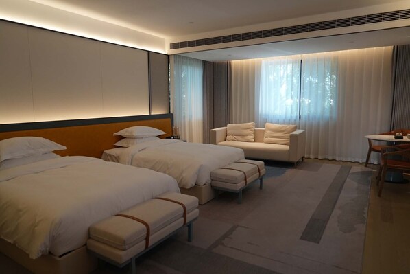 A hotel room with two beds, a sofa, a desk, and a large window with curtains. - XUANDE GATE HOTEL (Jiaxing)