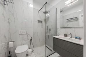 Ein modernes Badezimmer mit einer Duschkabine, einer Toilette und einem Waschtisch mit Spiegel.