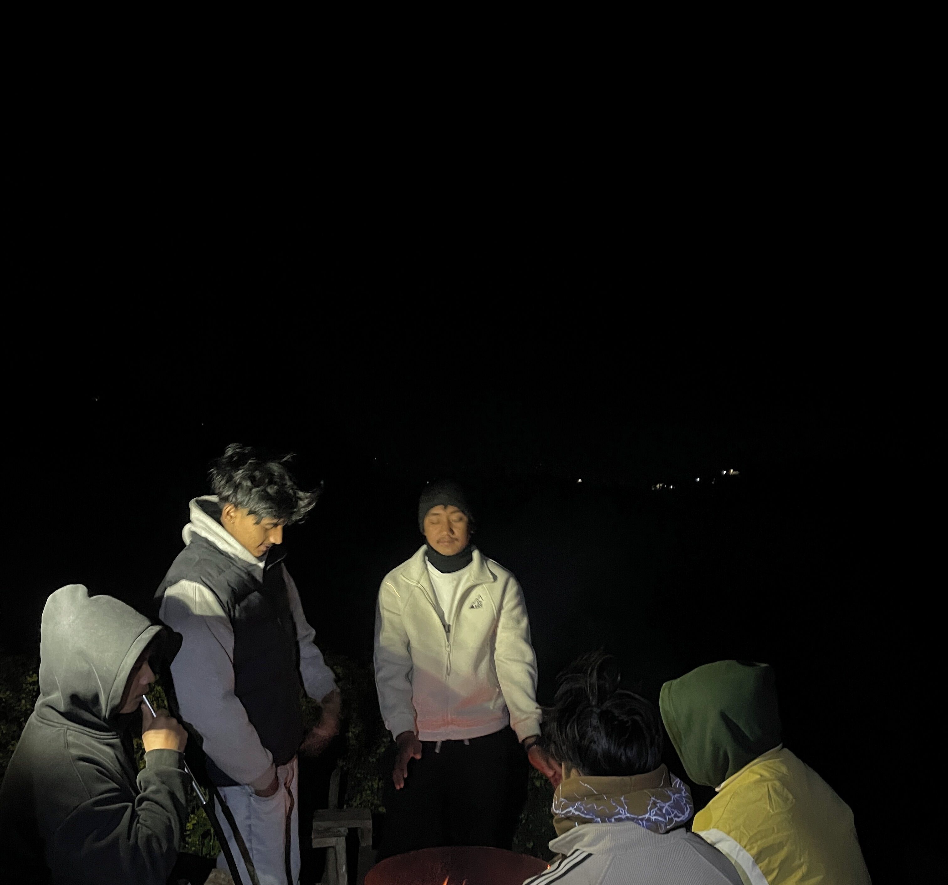 Un groupe de personnes se trouve à l'extérieur, de nuit.