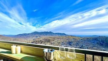 A wooden deck with a view of mountains and a cityscape.