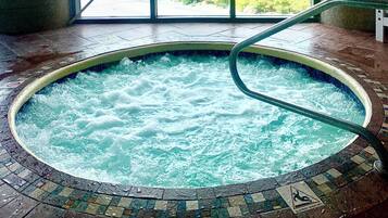 A hot tub with a tiled floor and a safety sign indicating slippery when wet.