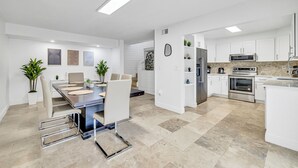 A modern kitchen with white cabinetry, stainless steel appliances, and a dining area with a table and chairs. - Rare Brickell Miami House - Walk to Nightlife / Dining / Shopping (Miami)