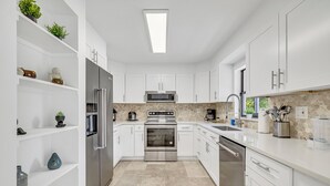 A modern kitchen with white cabinets, stainless steel appliances, and a tiled backsplash. - Rare Brickell Miami House - Walk to Nightlife / Dining / Shopping (Miami)