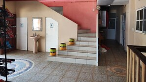 A staircase with a red wall, a sink, and three barrels. - Hotel Ricarda Yopes (Acapulco)
