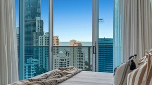 Habitació d'hotel amb una finestra gran que dona a una vista panoràmica de la ciutat i del mar.