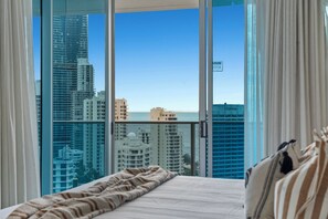 Ein Hotelzimmer mit großem Fenster und Blick auf Stadt und Meer.