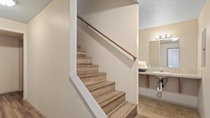 A staircase leading to a bathroom with a vanity, mirror, and lighting. - Spacious and comfortable 5-bedroom house near Whitworth University (Spokane)