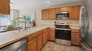 A modern kitchen with wooden cabinets, stainless steel appliances, and a dishwasher. - Spacious and comfortable 5-bedroom house near Whitworth University (Spokane)