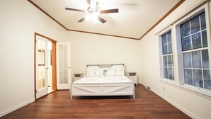 A bedroom with a bed, a ceiling fan, a window, and a door.