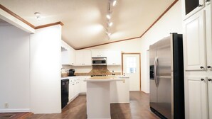 A kitchen with white cabinets, a central island, a stainless steel refrigerator, and a microwave.
