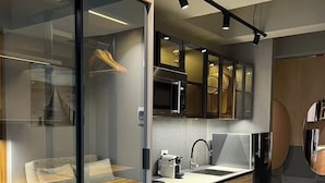 Une cuisine moderne équipée d’un four à micro-ondes, d’un évier et de meubles de rangement en bois. On y trouve également un coin repas avec une table et des chaises, ainsi qu’un canapé.