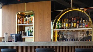 Un espace bar doté d’un comptoir en bois, de tabourets de bar et d’une variété de bouteilles et de verres.