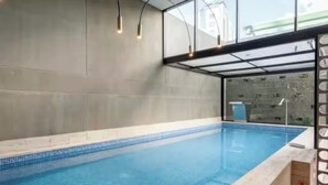 Une piscine dotée d’un bord carrelé, d’une enceinte en verre et d’une structure métallique.