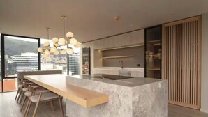 Une cuisine moderne dotée d’un grand îlot central, de chaises en bois, d’un évier encastré et offrant une vue sur la ville.