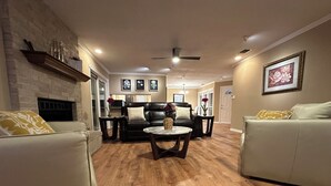 A living room with a fireplace, leather sofas, a coffee table, and a ceiling fan. - A&C WATERFORD COTTAGE # 3 (Victoria)