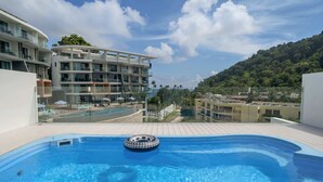A rooftop swimming pool with a hot tub, surrounded by a modern building with balconies and a view of a hillside. - Absolute Twin Sands 5404 Private Pool (Patong)